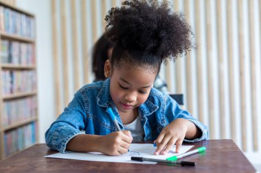 Girl is doing homework in the Classroom. Back to school! Cute industrious children are sitting at desks indoors. Kids are learning in class.