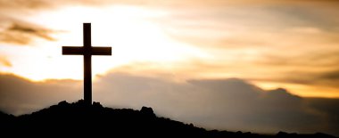The silhouette cross standing on meadow sunset and flare background.Cross on a hill as the morning sun comes up for the day.The cross symbol for Jesus christ. Christianity, religious, faith, Jesus .