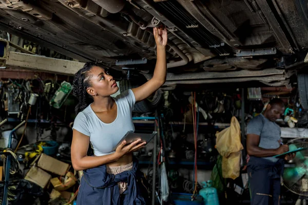 Professional Car Mechanic is Investigating Under a Vehicle on a Lift in Service. Auto Service Worker Checking Car Under Carriage Look For Issues. Car service technician check and repair customer car.