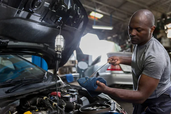Car mechanic checking  oil quality the engine motor car Transmission and Maintenance Gear. car mechanic in an auto repair shop is checking the engine.