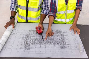 Engineers with draft plan of building on constructing site. Engineer working on building site. Engineer working with drawing System plan document