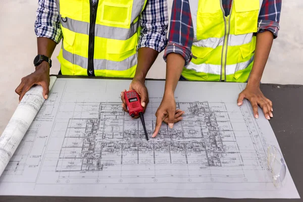 Engineers with draft plan of building on constructing site. Engineer working on building site. Engineer working with drawing System plan document