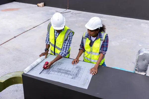 Engineers with draft plan of building on constructing site. Engineer working on building site. Engineer working with drawing System plan document