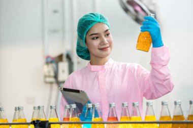 Woman worker using Checking quality or checking stock of products in beverage factory. Worker QC working in a drink water factory