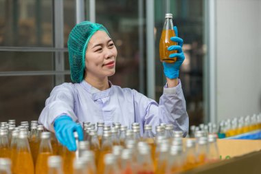 Woman worker using Checking quality or checking stock of products in beverage factory. Worker QC working in a drink water factory