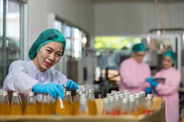 Woman worker using Checking quality or checking stock of products in beverage factory. Worker QC working in a drink water factory
