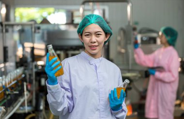 Woman worker using Checking quality or checking stock of products in beverage factory. Worker QC working in a drink water factory