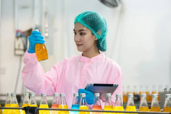 Woman worker using Checking quality or checking stock of products in beverage factory. Worker QC working in a drink water factory