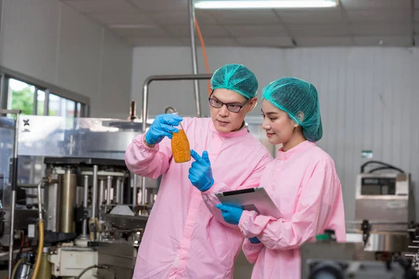 Woman worker using Checking quality or checking stock of products in beverage factory. Worker QC working in a drink water factory