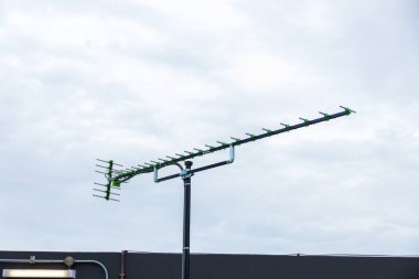 Gökyüzü arka planlı televizyon antenleri. Çatıda analog televizyon anteni. Dijital Tv ve radyo alımı için anten. Gün batımında mobil iletişim antenleri.