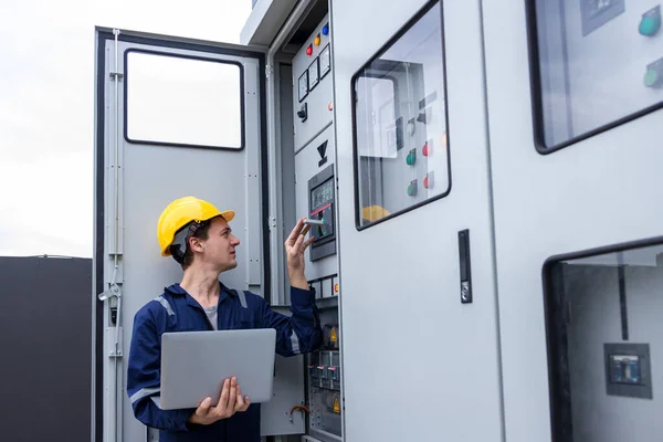 Electrical engineer working in control room. Electrical engineer man checking Power Distribution Cabinet in the control room