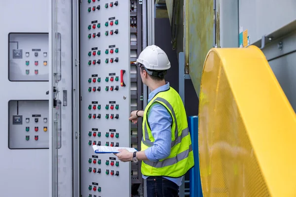 Electrical engineer working in control room. Electrical engineer man checking Power Distribution Cabinet in the control room