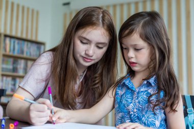 Girl is doing homework in the Classroom. Back to school! Cute industrious children are sitting at desks indoors. Kids are learning in class.