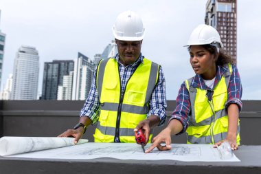 Engineers with draft plan of building on constructing site. Engineer working on building site. Engineer working with drawing System plan document