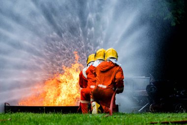 Firefighter Concept. Fireman using water and extinguisher to fighting with fire flame. firefighters fighting a fire with a hose and water during a firefighting training exercise