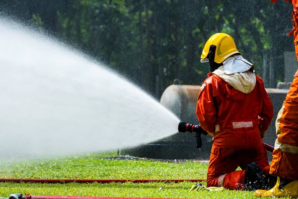 Fire man spray water from hose for fire fighting. Firefighter spraying a straight steam