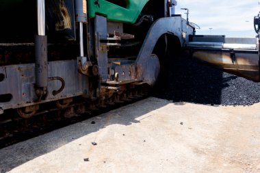 Paver machine on a new asphalt road surface. Laying of a new asphalt pavement on a city street with the use of machinery.