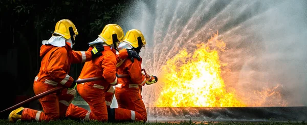 Firefighter Concept. Fireman using water and extinguisher to fighting with fire flame. firefighters fighting a fire with a hose and water during a firefighting training exercise