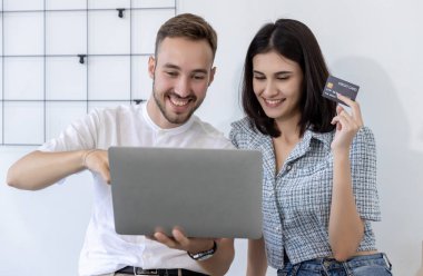 Evde kredi kartı ve dizüstü bilgisayar alan bir çift. Kadın ve Adam ellerinde kredi kartıyla çevrimiçi nakliye yapıyor. İnternetten kredi kartı alışverişi yapan çift.