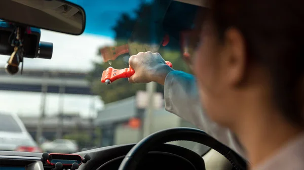 Woman use Safety Hammer and Seatbelt Cutter in Cars, break glass When emergency. In case of emergency on car safety red hammers to break the grass window.