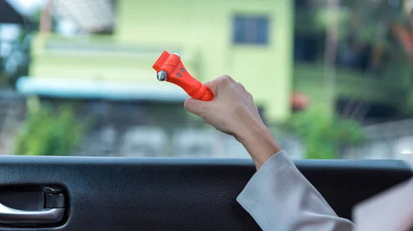 Woman use Safety Hammer and Seatbelt Cutter in Cars, break glass When emergency. In case of emergency on car safety red hammers to break the grass window.