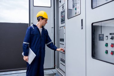 Kontrol odasında çalışan elektrik mühendisi. Elektrik mühendisi kontrol odasındaki güç dağıtım dolabını kontrol ediyor.