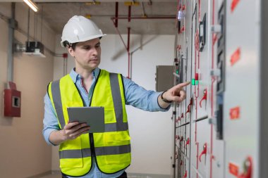 Kontrol odasında çalışan elektrik mühendisi. Elektrik mühendisi kontrol odasındaki güç dağıtım dolabını kontrol ediyor.