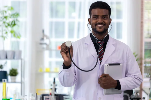 Doctor holding stethoscope at scientific lab. Friendly male doctor dressed in uniform holding stethoscope. Doctor in a dressing gown with a stethoscope examination in the hands.