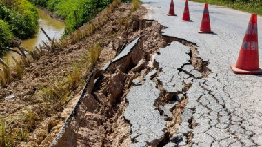 Yağmurun yol açtığı toprak kayması bozuk yol asfaltında meydana gelir. Kırık asfalt yol çöktü ve düştü. Yol çöker. Çatlak asfalt yol. İnşaat alanı.