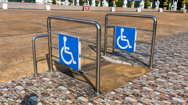 Disabled way sign in front of building. Handicapped sign traffic symbol on the floor in front of ramp way for support wheelchair. Disabled way sign in front of cafe on green nature landscape.