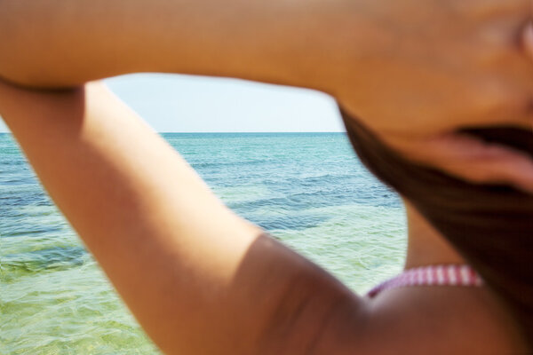 Brunette girl on the beach under the bright sun tans