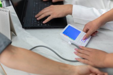 Hemşire tansiyonunu ölçmek için elektronik tansiyon monitörünü açar..