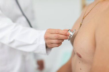 Ofiste, doktor atletik bir adamın akciğerlerine bakıyor..
