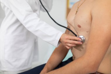 Ofiste, doktor atletik bir adamın akciğerlerine bakıyor..