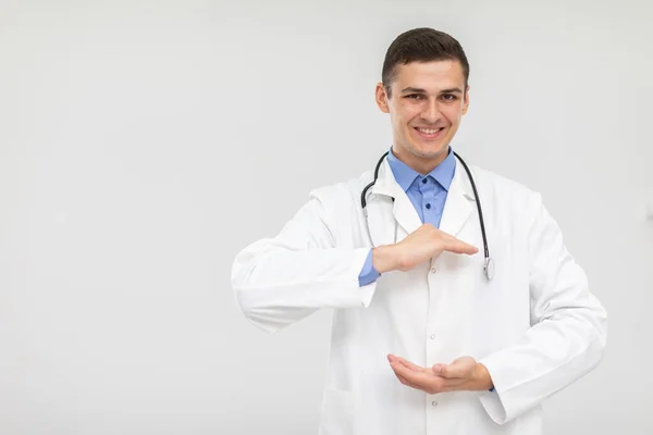 Uśmiechnięty lekarz stoi do przodu i podnosi ręce, by reklamować nowy produkt.. — Zdjęcie stockowe