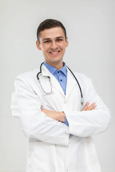 Dokter yang tersenyum berdiri ke depan dengan tangan terlipat dalam senyum lembut. — Stok Foto