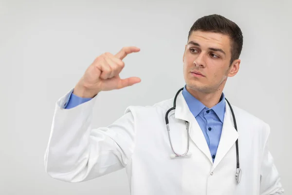 Un médico sostiene un espacio en blanco en dos dedos para promover un nuevo producto. —  Fotos de Stock