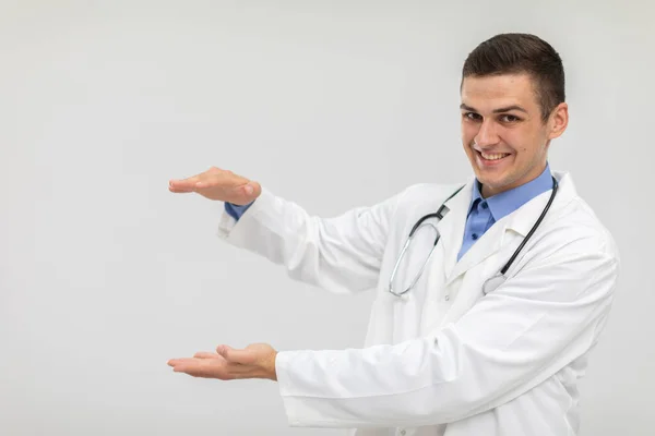 Um médico sorrindo está à frente e tem as mãos levantadas para anunciar um novo produto. — Fotografia de Stock