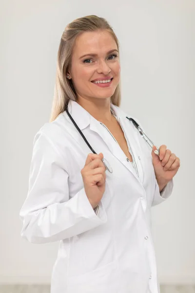 Un medico sorridente si alza di fronte alla macchina fotografica e tiene uno stetoscopio tra le mani. — Foto Stock