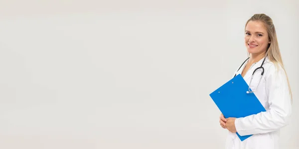 A mosolygó orvos egy kék mappában tartja a dokumentumokat. Panorámakeret. — Stock Fotó