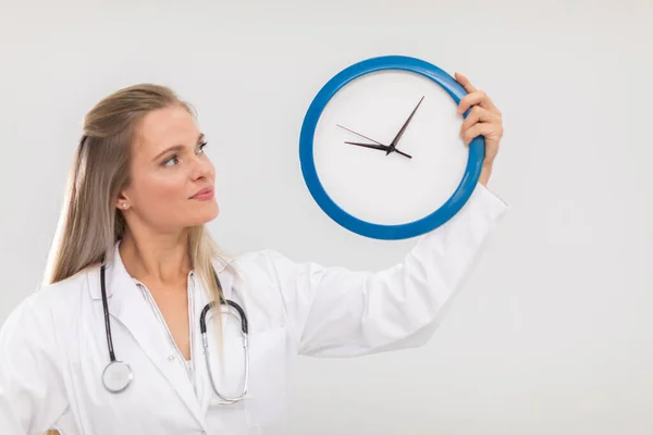 Doktorka drží v rukou nástěnné hodiny a připomíná vám, že je čas na léčbu. — Stock fotografie
