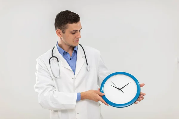 Il medico tiene tra le mani un orologio da parete che misura il tempo quotidiano. — Foto Stock