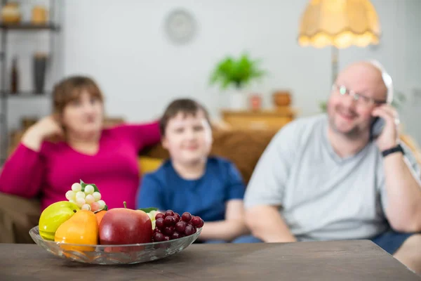 A mesa marrom e seu delicioso suporte de frutas e no sofá fica uma família pronta para perder peso. — Fotografia de Stock