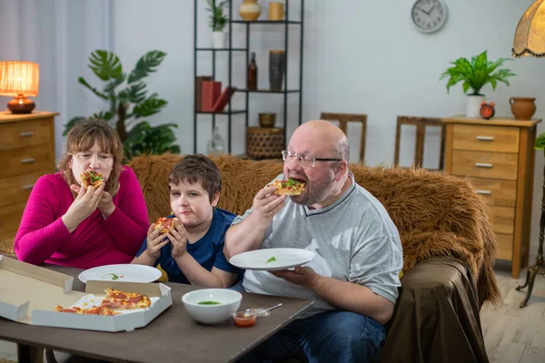 A família come fatia após fatia de deliciosa pizza quente. — Fotografia de Stock