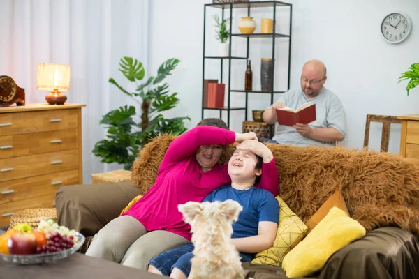 Mãe está brincando com seu filho no sofá e pai está lendo um livro. — Fotografia de Stock