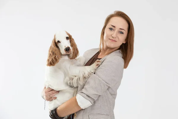 Una mujer sostiene a un perro en sus brazos y ambos miran a la cámara. Inglés cocker spaniel with honey gold coat. — Foto de Stock