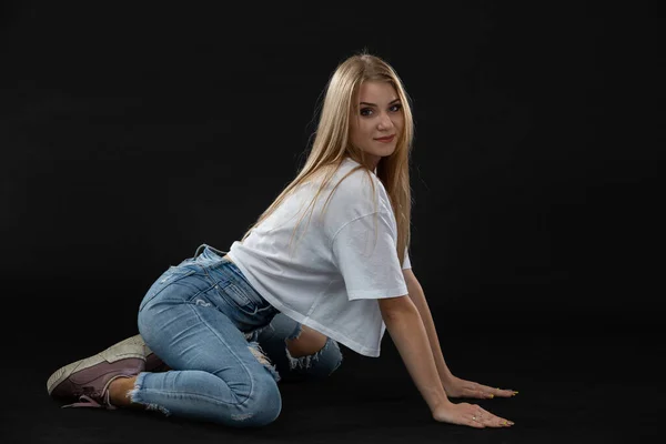 Una bailarina adolescente se sienta en el suelo con su lado mirando a la cámara. Cabello largo y rubio. — Foto de Stock