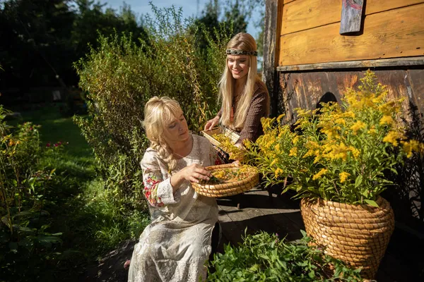 Dos mujeres, una joven y la otra mayor cáscara de oro varilla de flores en una cesta. —  Fotos de Stock