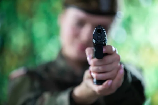 The lady soldier aims straight at the camera with a short gun. — Stock Photo, Image