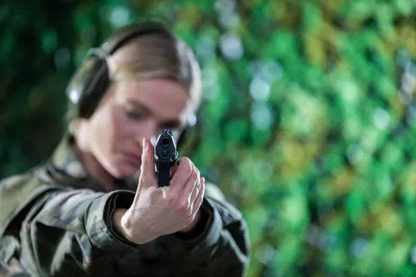 射击场上的女兵用枪瞄准耳朵上戴着耳机的目标. — 图库照片